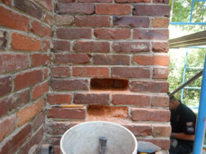 bucket in front of chimney with missing bricks