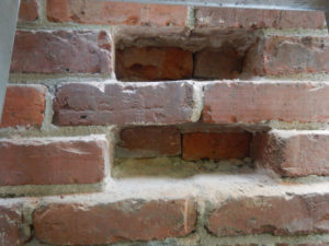 close up of two bricks missing from masonry